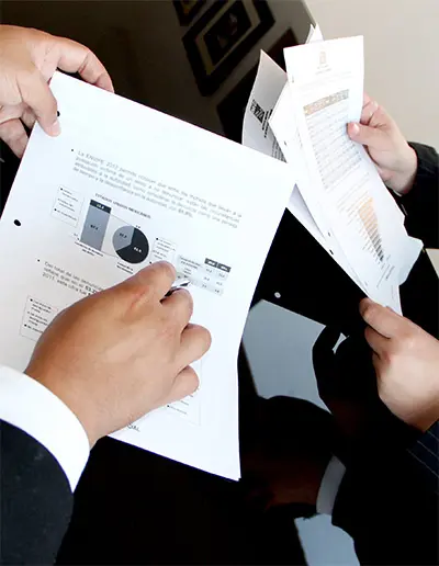 Deux personnes en tenue professionnelle consultant des documents avec graphiques et diagrammes